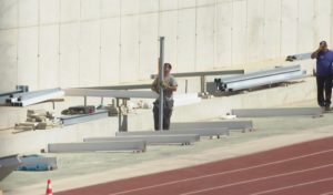 Operarios empiezan a colocar las estructuras para las gradas en la pista de atletismo
