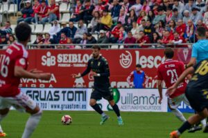 Cristian Rodríguez, con el balón, antes dos jugadores del Murcia 
